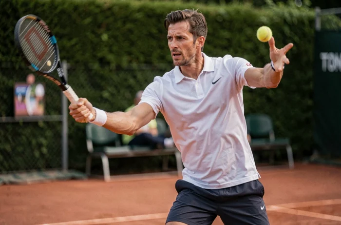 Joueur de tennis masculin au service sur un court en terre battue, évoquant les grands champions dont le nom commence par Z